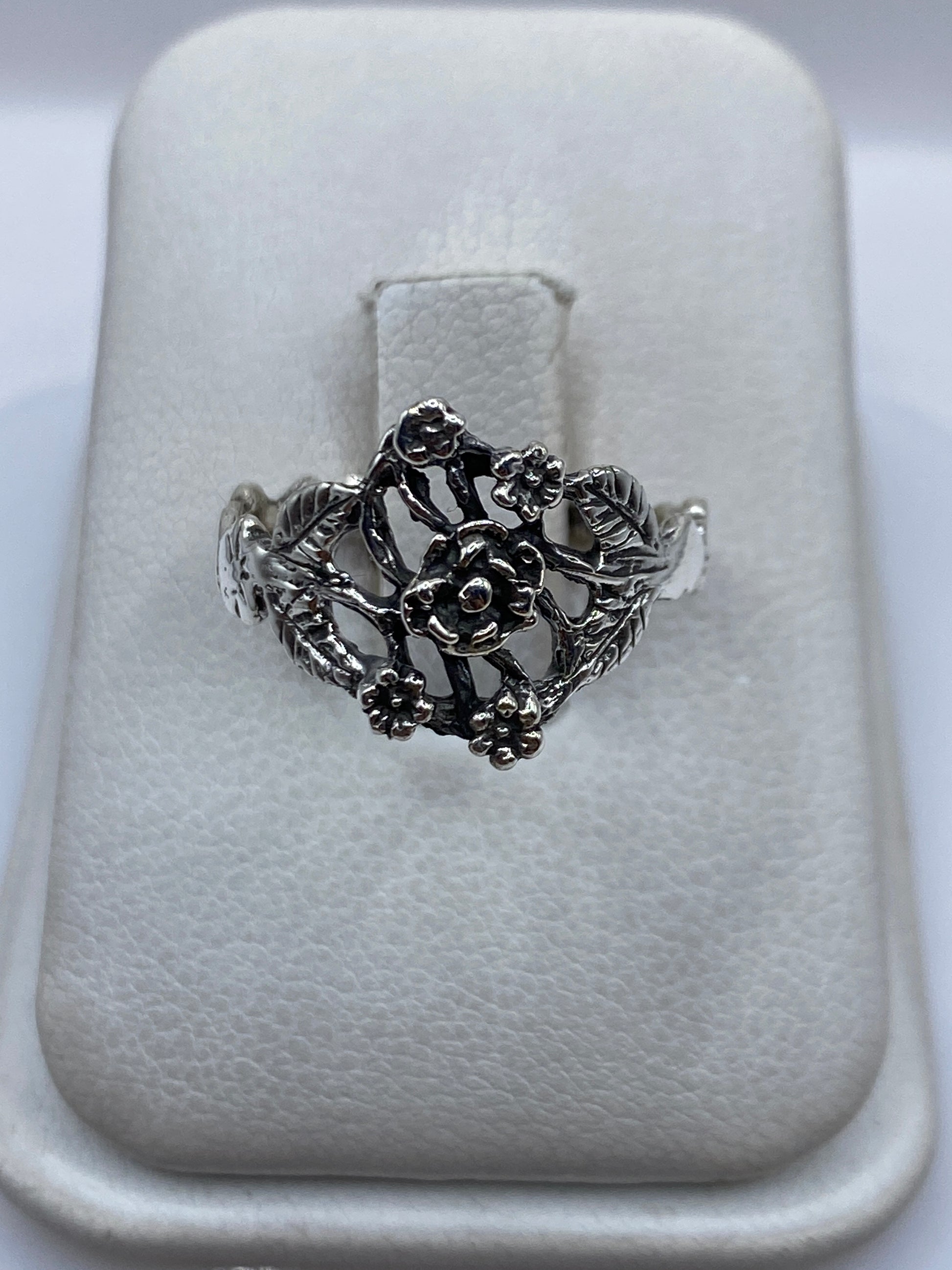Anillo de plata en calado con flores tridimensionales sobre estuche blanco