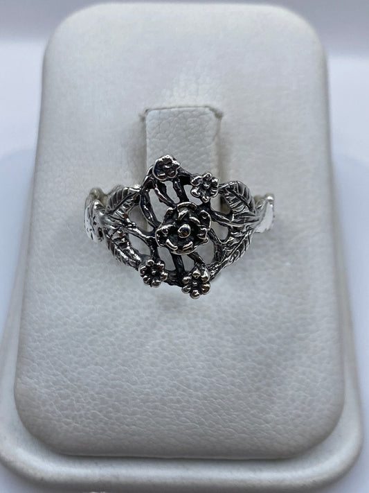 Anillo de plata en calado con flores tridimensionales sobre estuche blanco