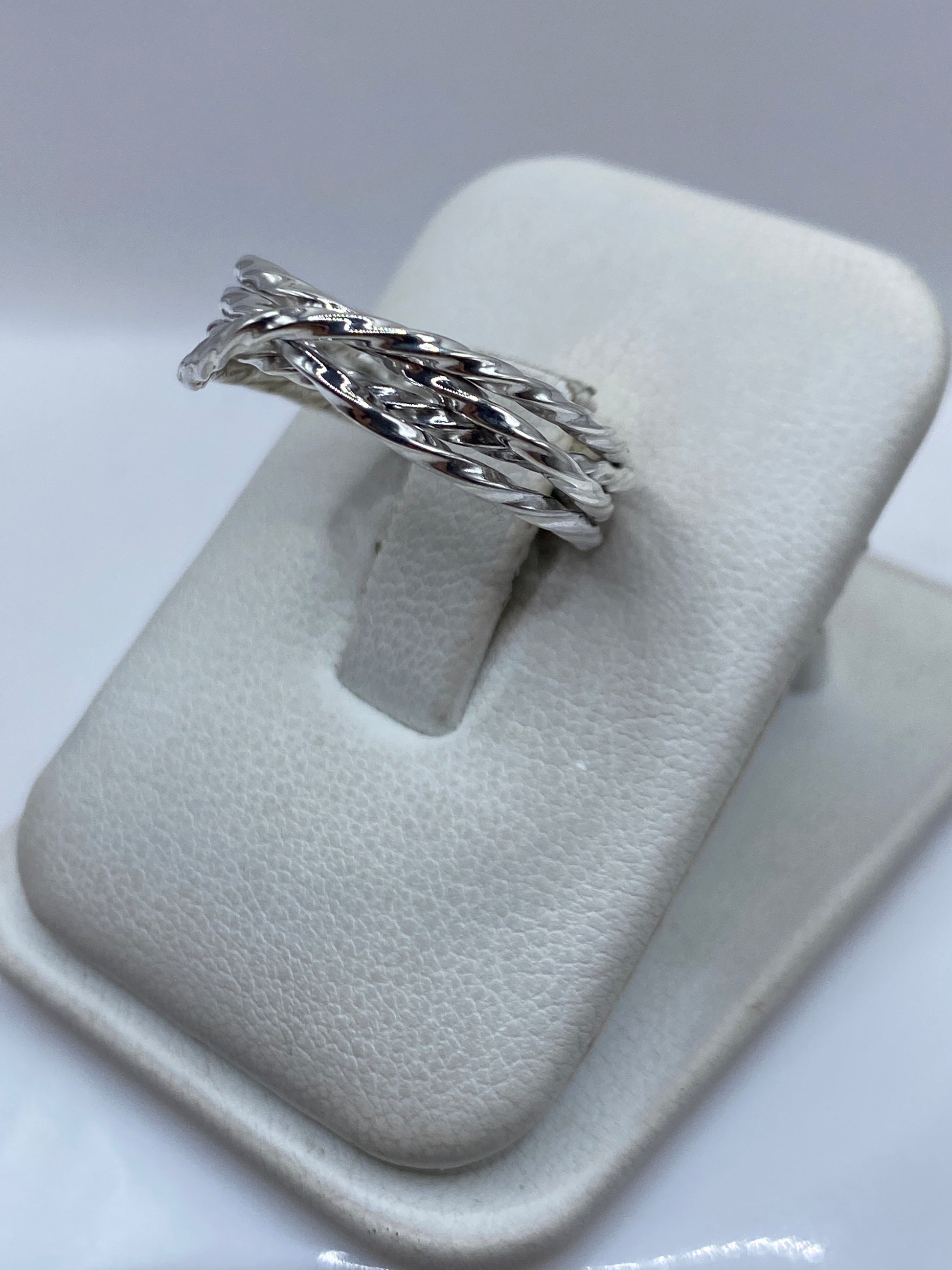 Anillo de plata .925 retorcido en el dedo de una mujer, mostrando el movimiento de las bandas