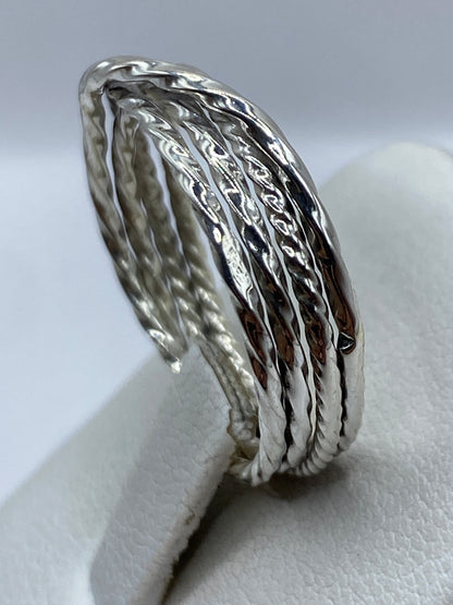 Anillo de plata retorcida puesto en dedo, brillo espejo