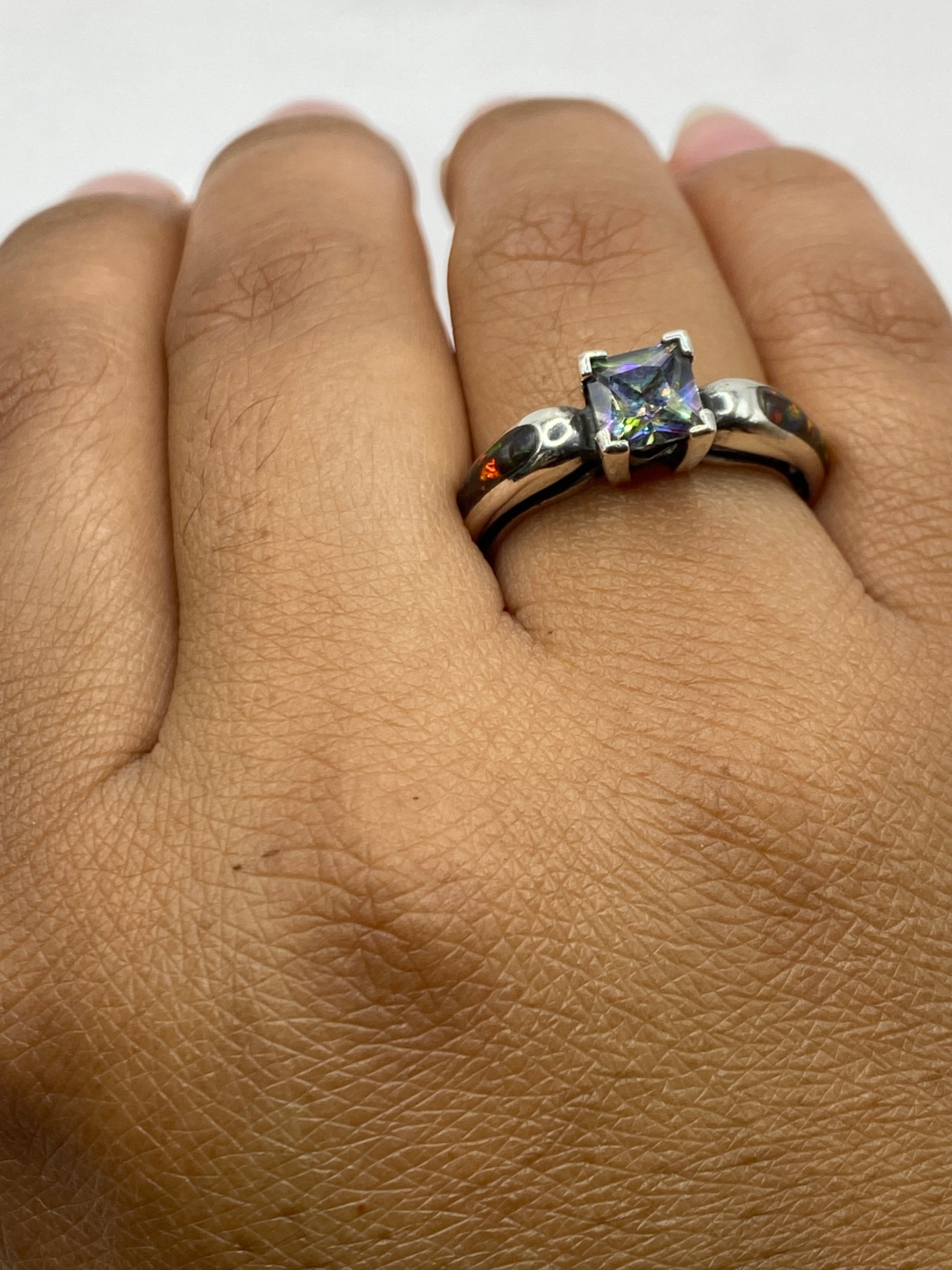 Anillo en la mano de una mujer mostrando cómo brilla el ópalo de fuego con la luz