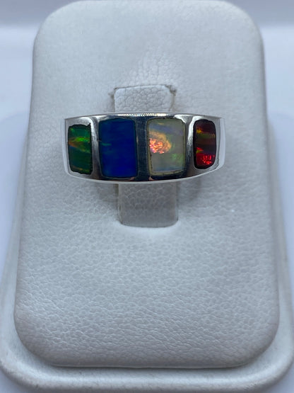 Anillo de plata con ópalo de fuego multicolor en tonos verde, azul y rojo sobre fondo blanco