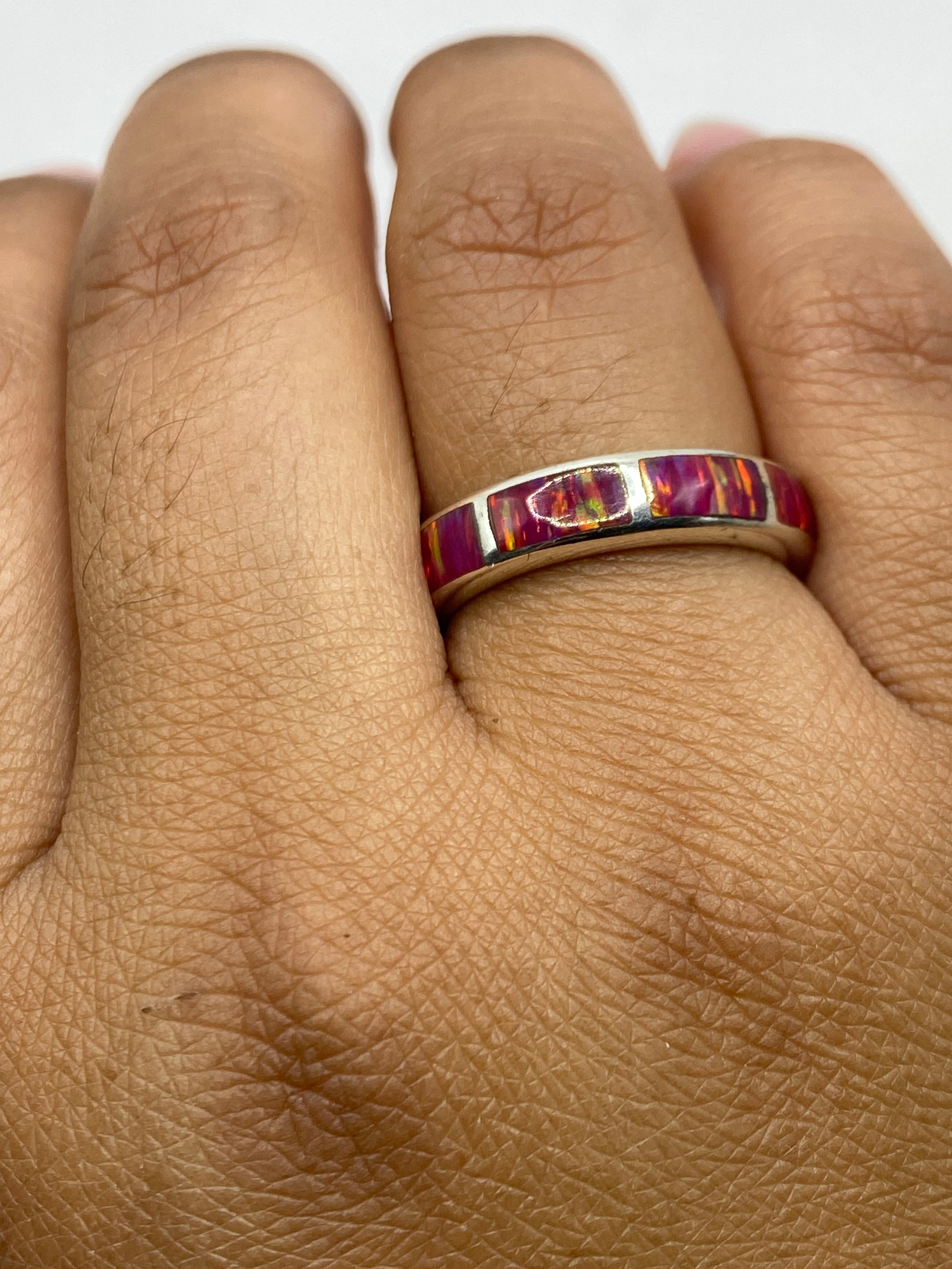 Anillo puesto en el dedo, mostrando el brillo y fuego del ópalo rosa contra la piel