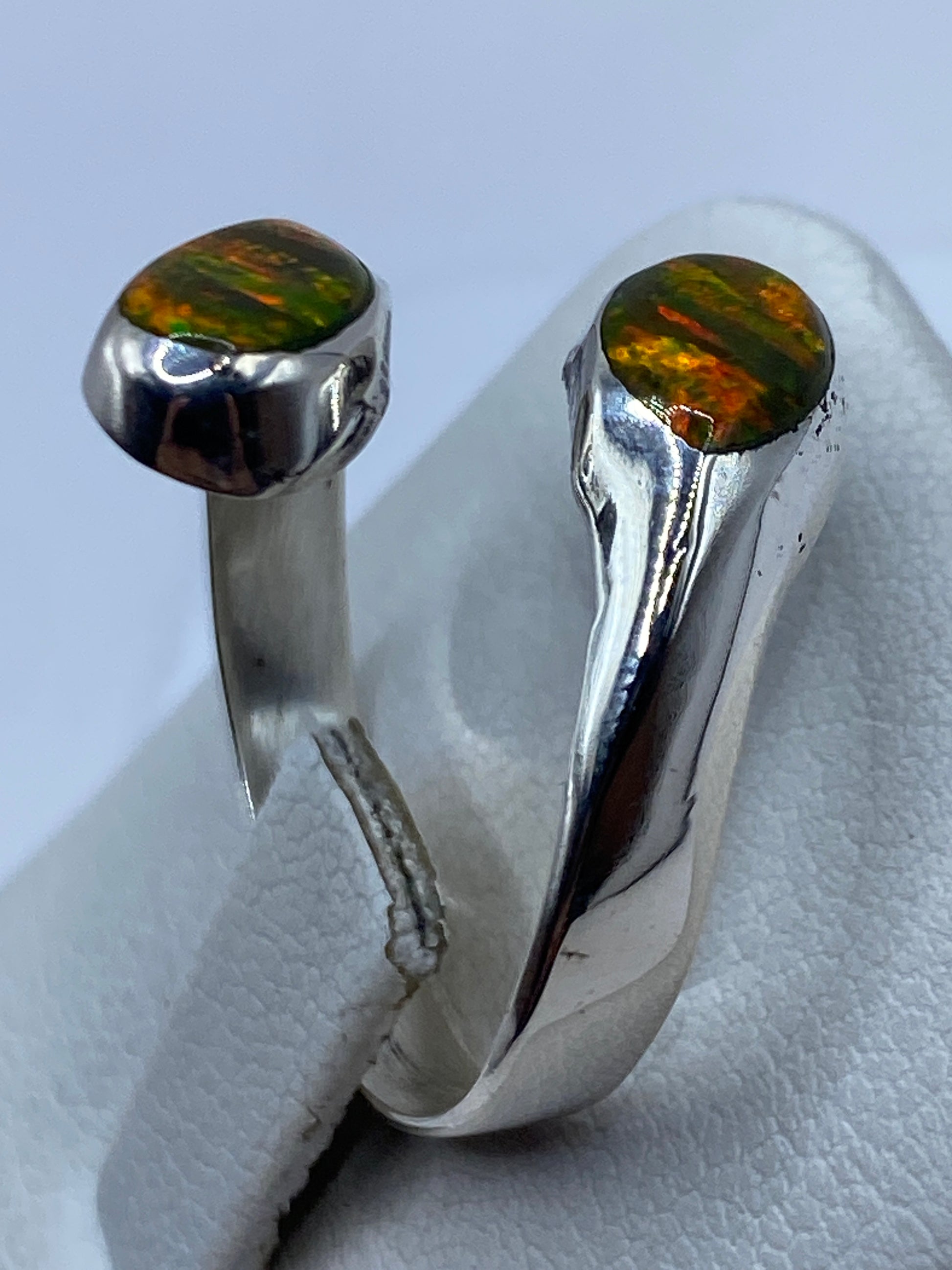 Anillo ajustable sobre dedo femenino con ópalo brillando en luz natural