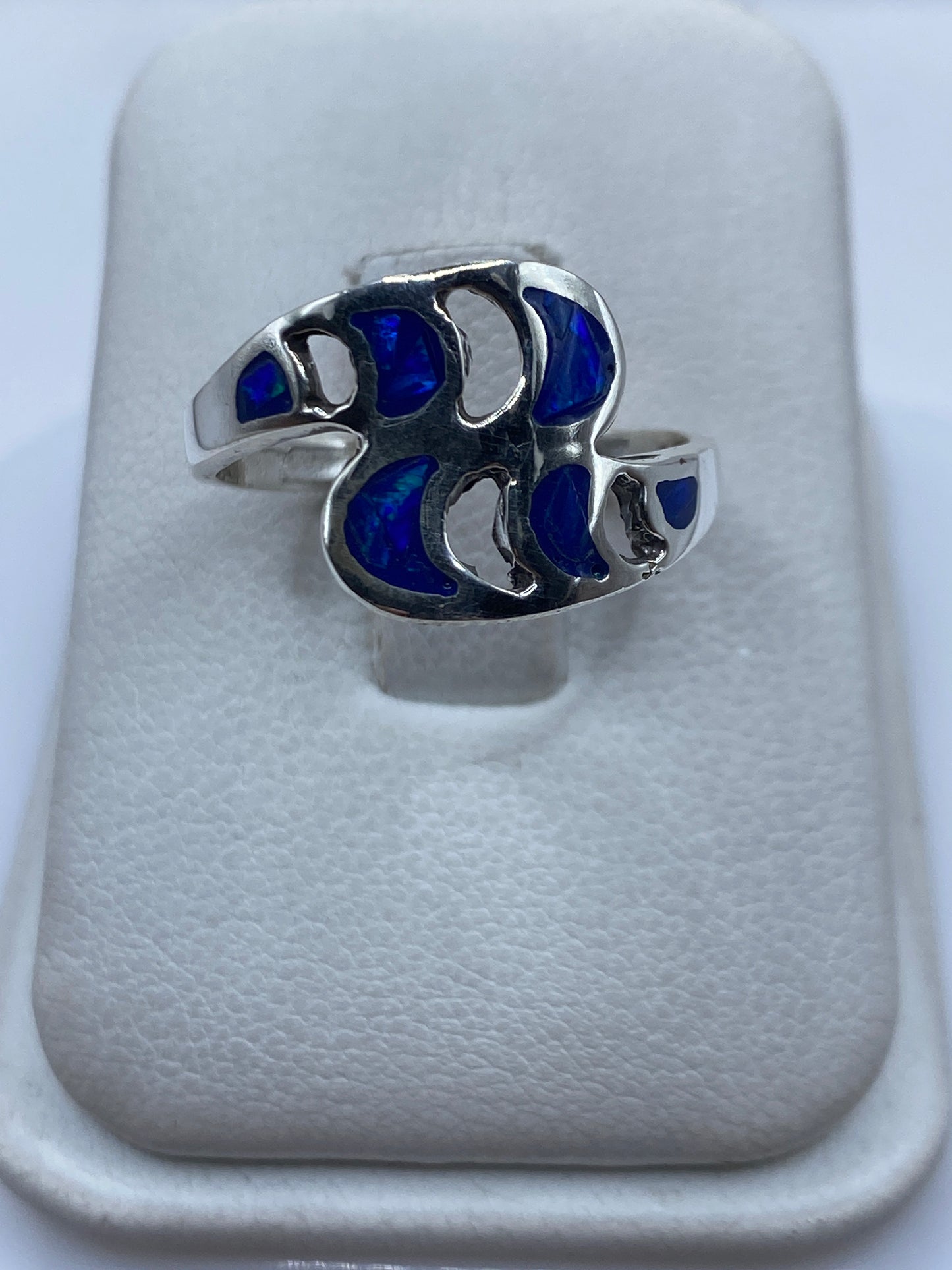 Anillo de plata con ópalo de fuego azul en la mano de una mujer