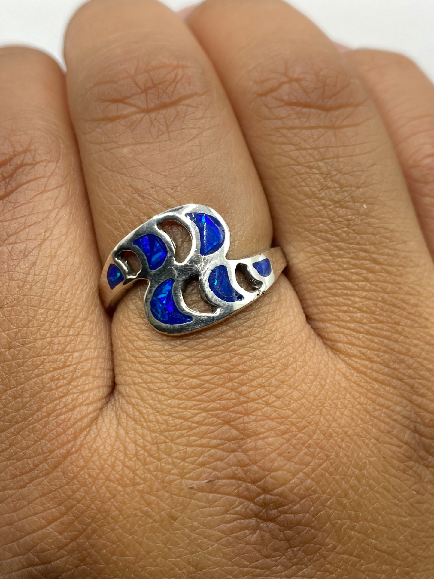 Anillo sobre superficie neutra iluminado para mostrar los reflejos azules del ópalo
