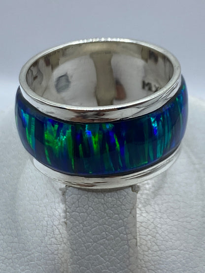 Anillo en dedo, mostrando el reflejo azul verdoso del ópalo y el acabado pulido de la banda
