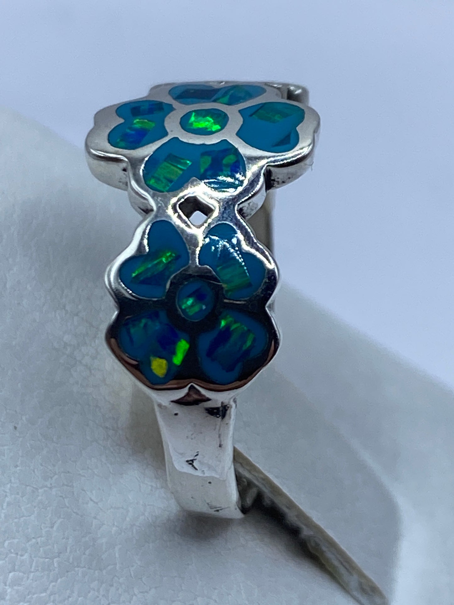 Anillo en dedo mostrando destellos verdes del ópalo de fuego