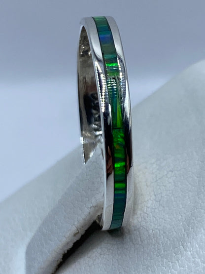Anillo unisex en dedo, mostrando el brillo verde y amarillo del ópalo