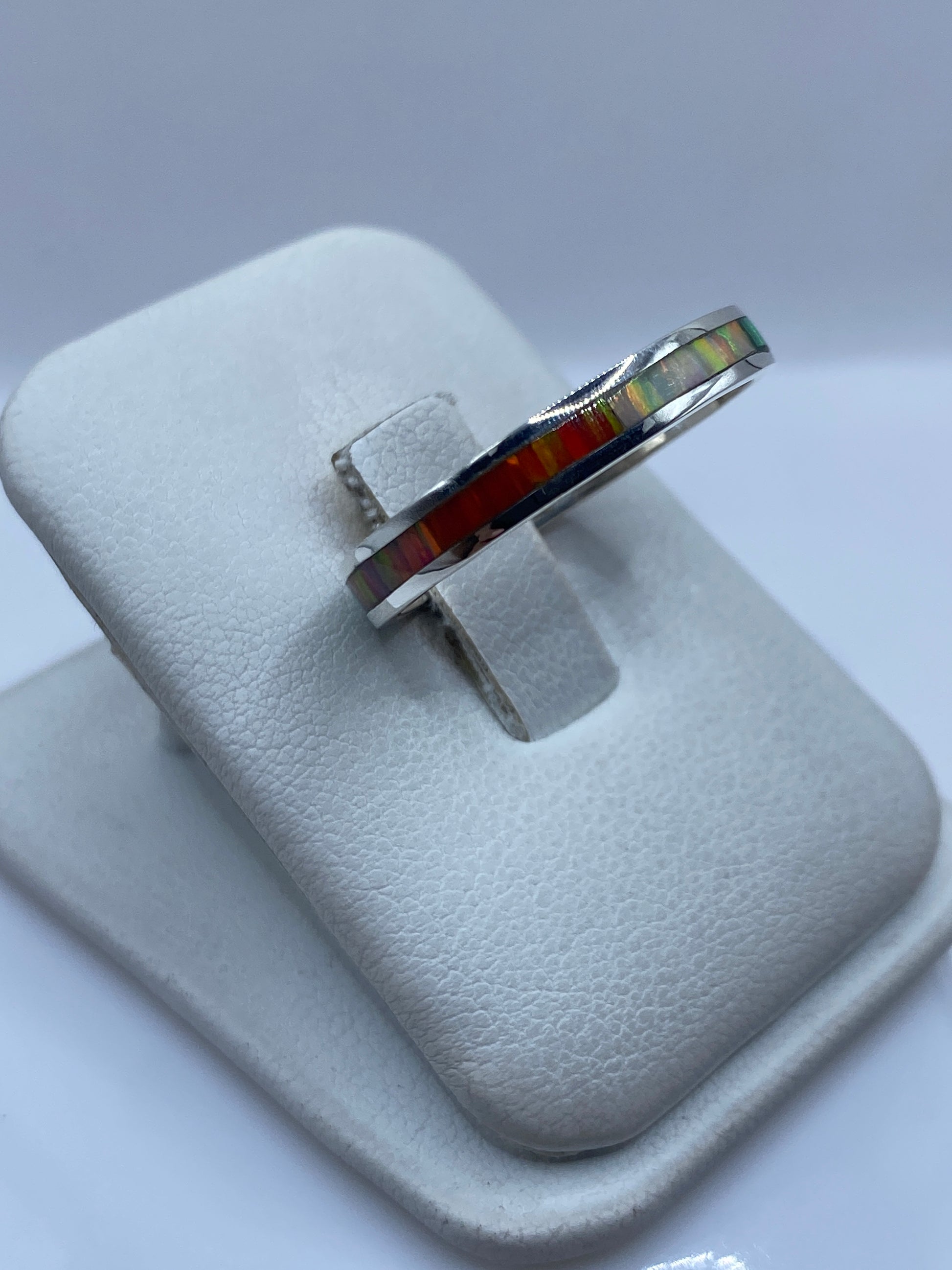 Detalle lateral del anillo mostrando el engaste a mano y los reflejos del ópalo