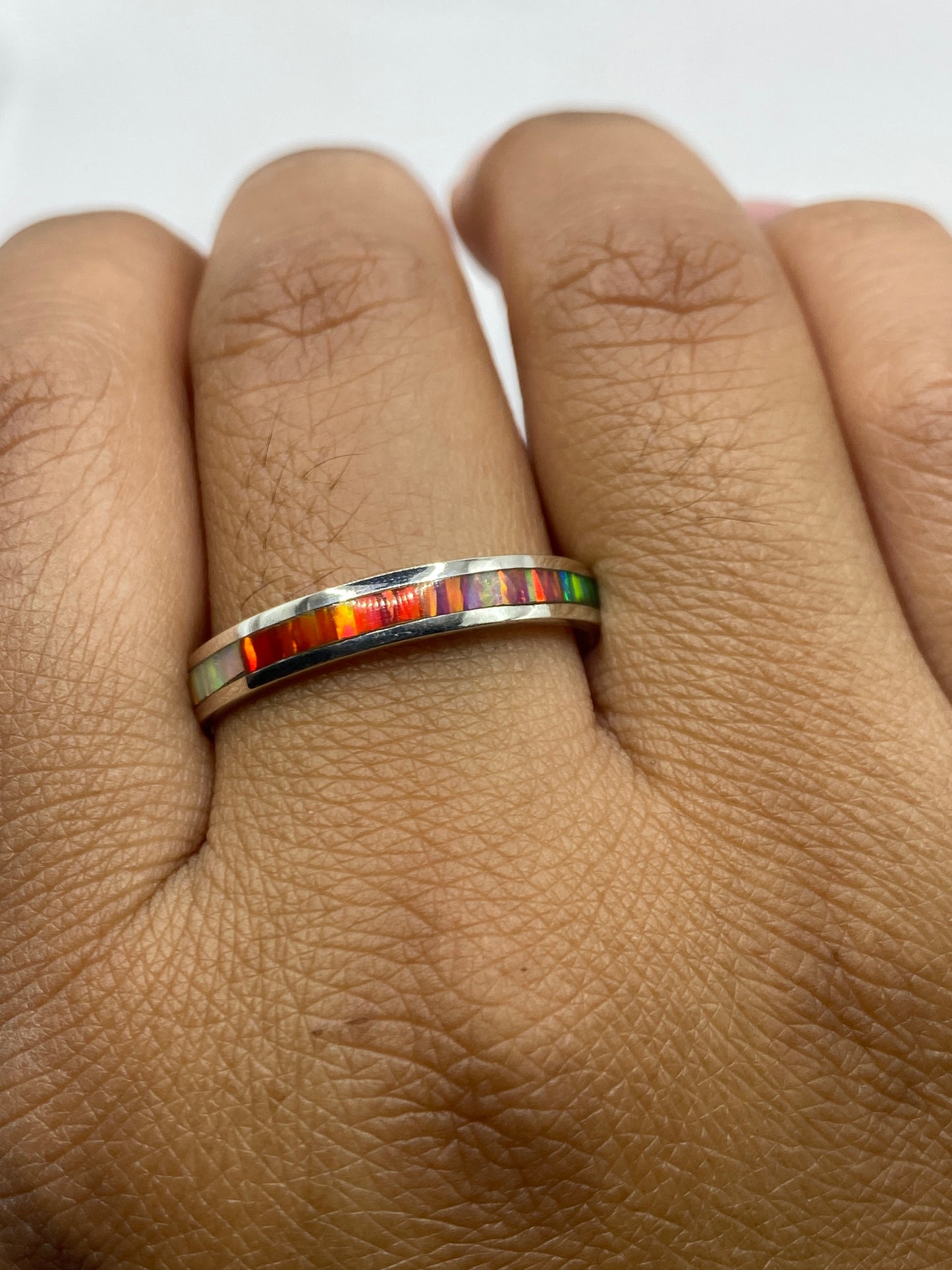 Anillo en la mano mostrando el Quinto .950 y cómo brilla el ópalo con la luz