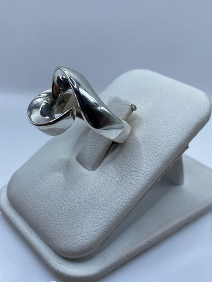 Anillo de plata moderno en dedo, mostrando el juego de volúmenes y luz
