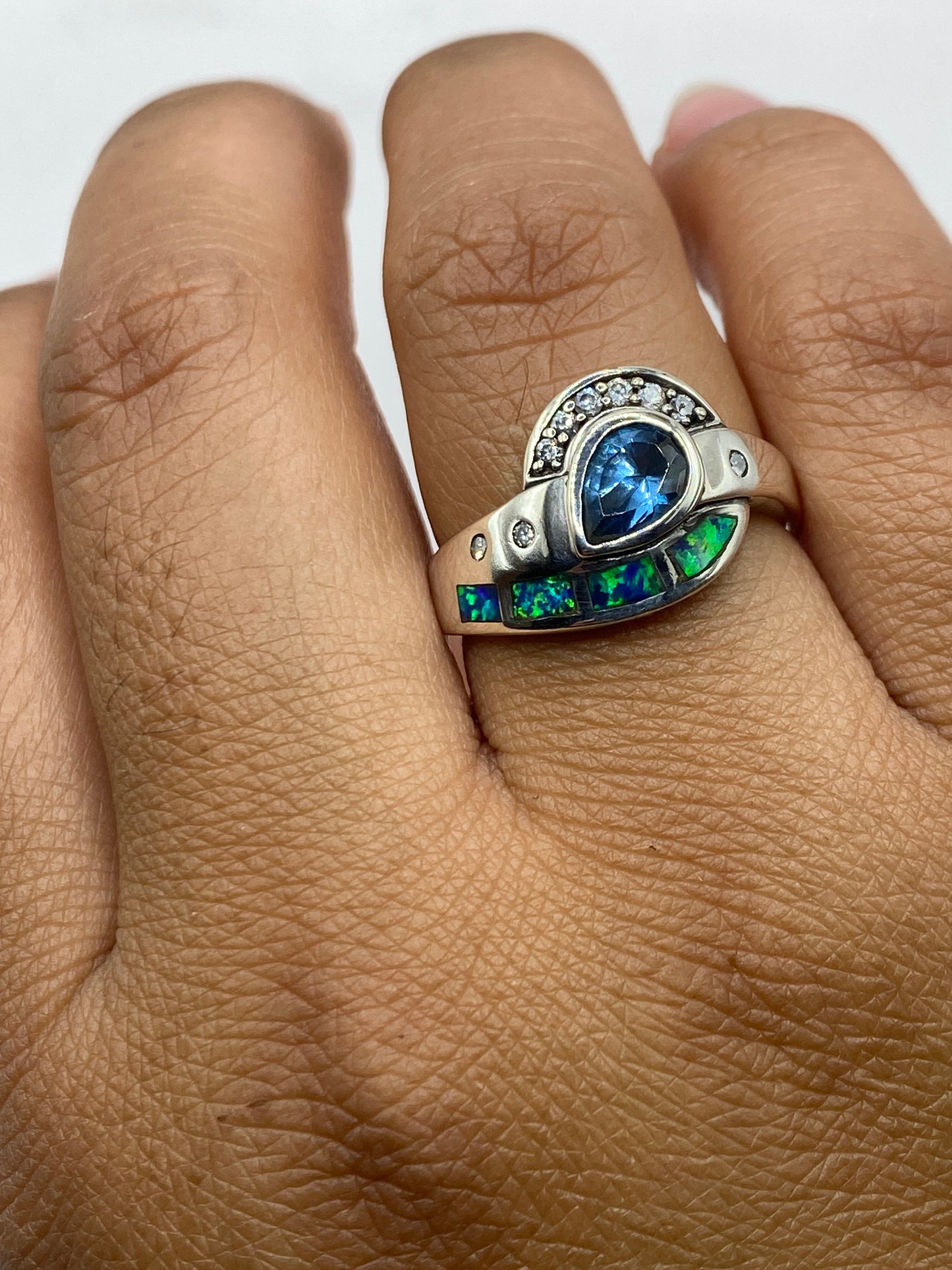 Anillo de plata con ópalo de fuego puesto en dedo, vista frontal del diseño combinado