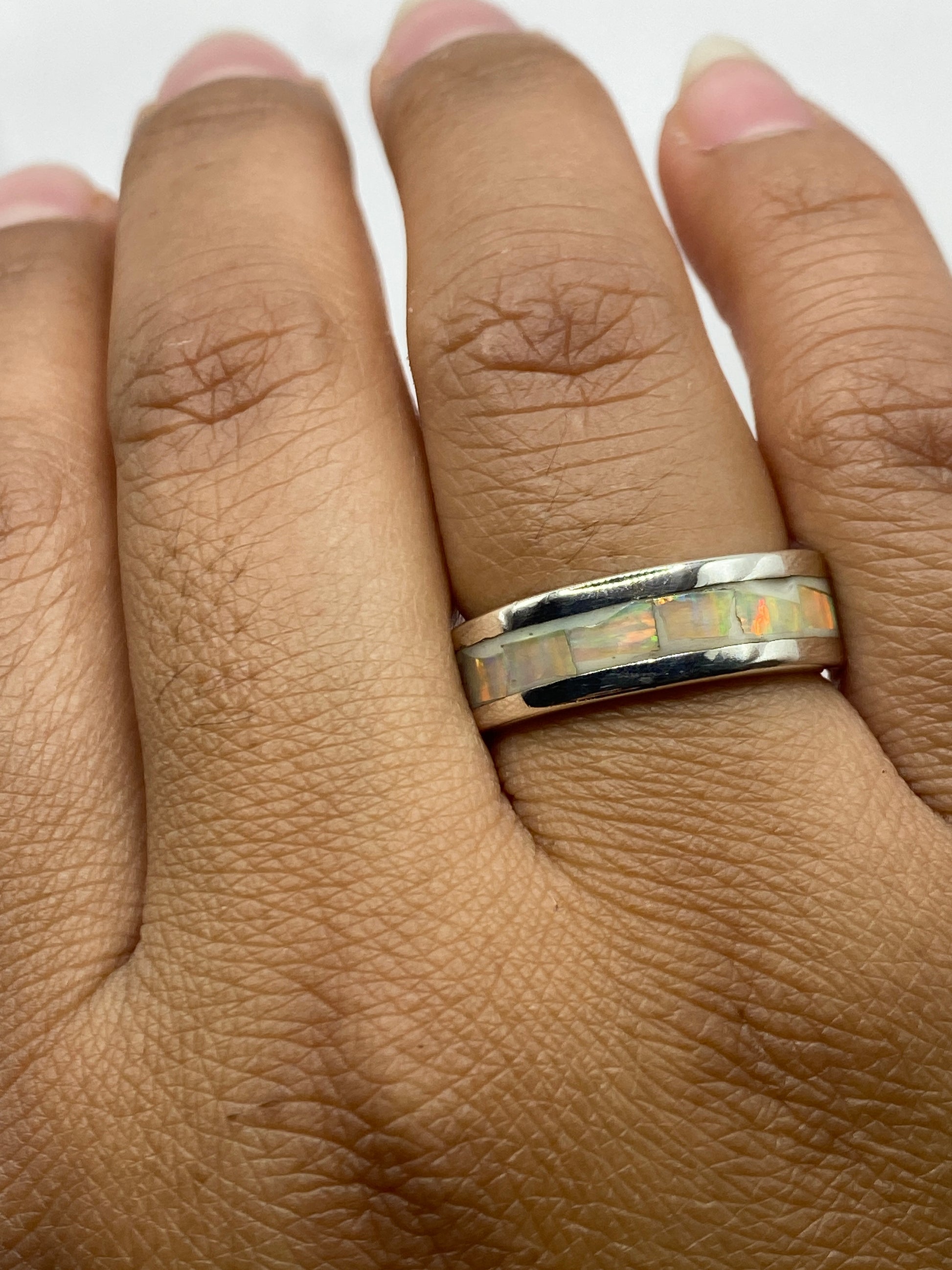 Anillo sobre dedo mostrando el juego de colores del ópalo bajo luz natural