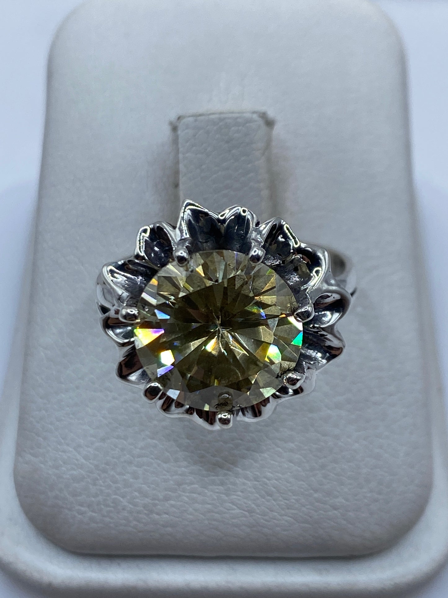Anillo de plata .925 con circonia amarillo verdoso engastada en corona floral, visto de frente en estuche blanco