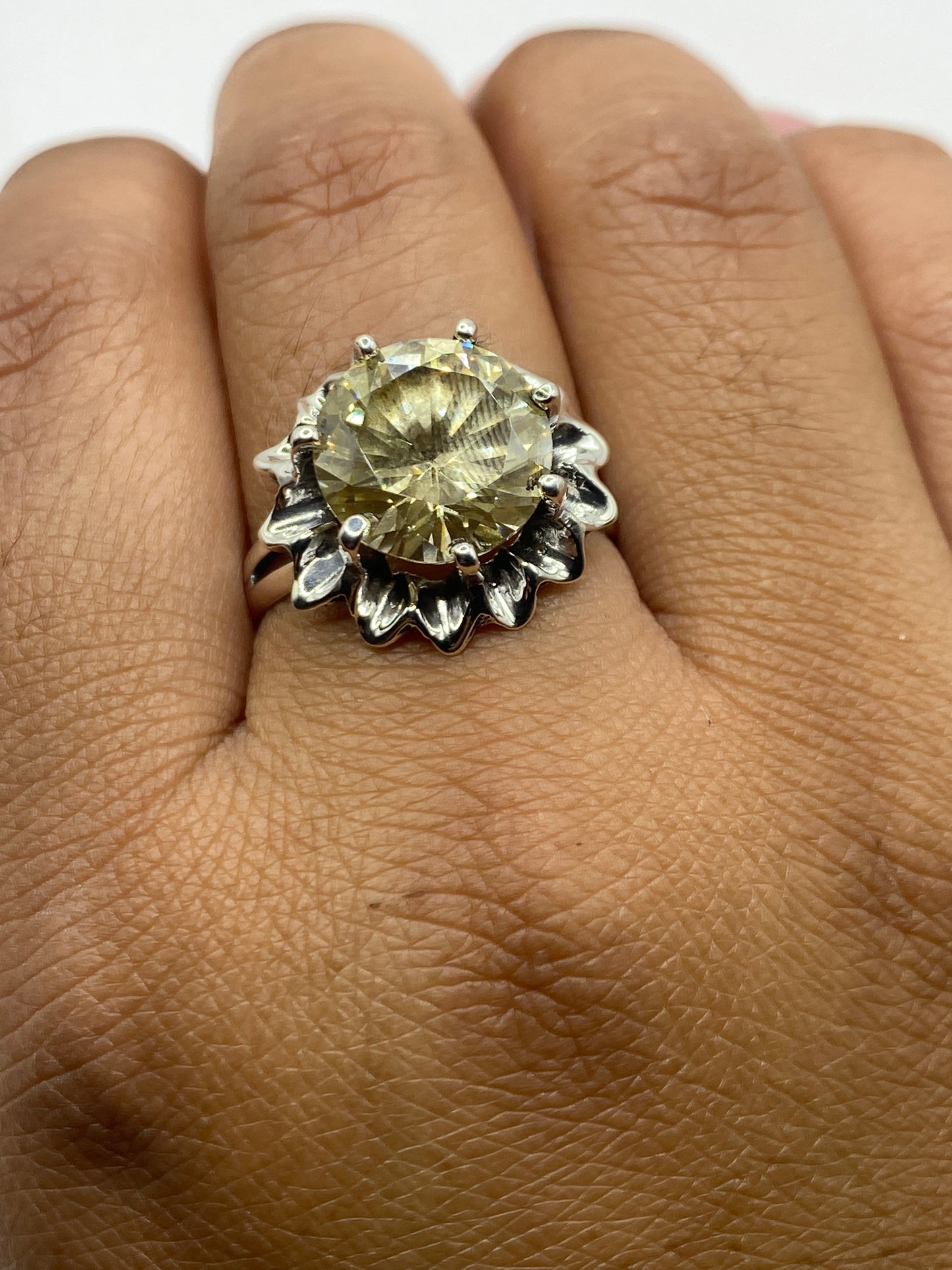 Anillo en la mano mostrando el brillo de la circonia amarillo verdoso bajo la luz