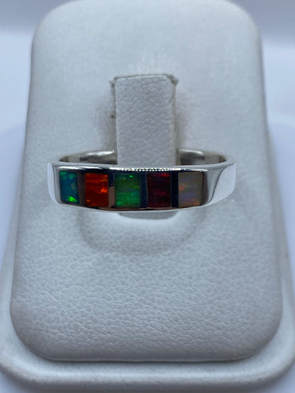 Anillo de plata .950 con ópalo de fuego multicolor en tonos naranja, rojo, amarillo y verde sobre fondo blanco
