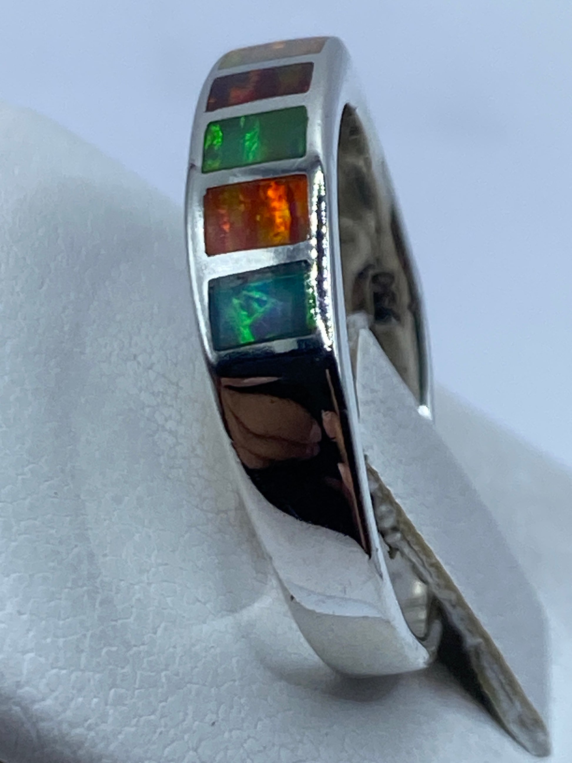 Anillo en la mano mostrando cómo juegan los colores del ópalo de fuego bajo la luz natural