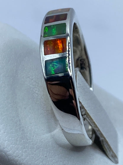 Anillo en la mano mostrando cómo juegan los colores del ópalo de fuego bajo la luz natural