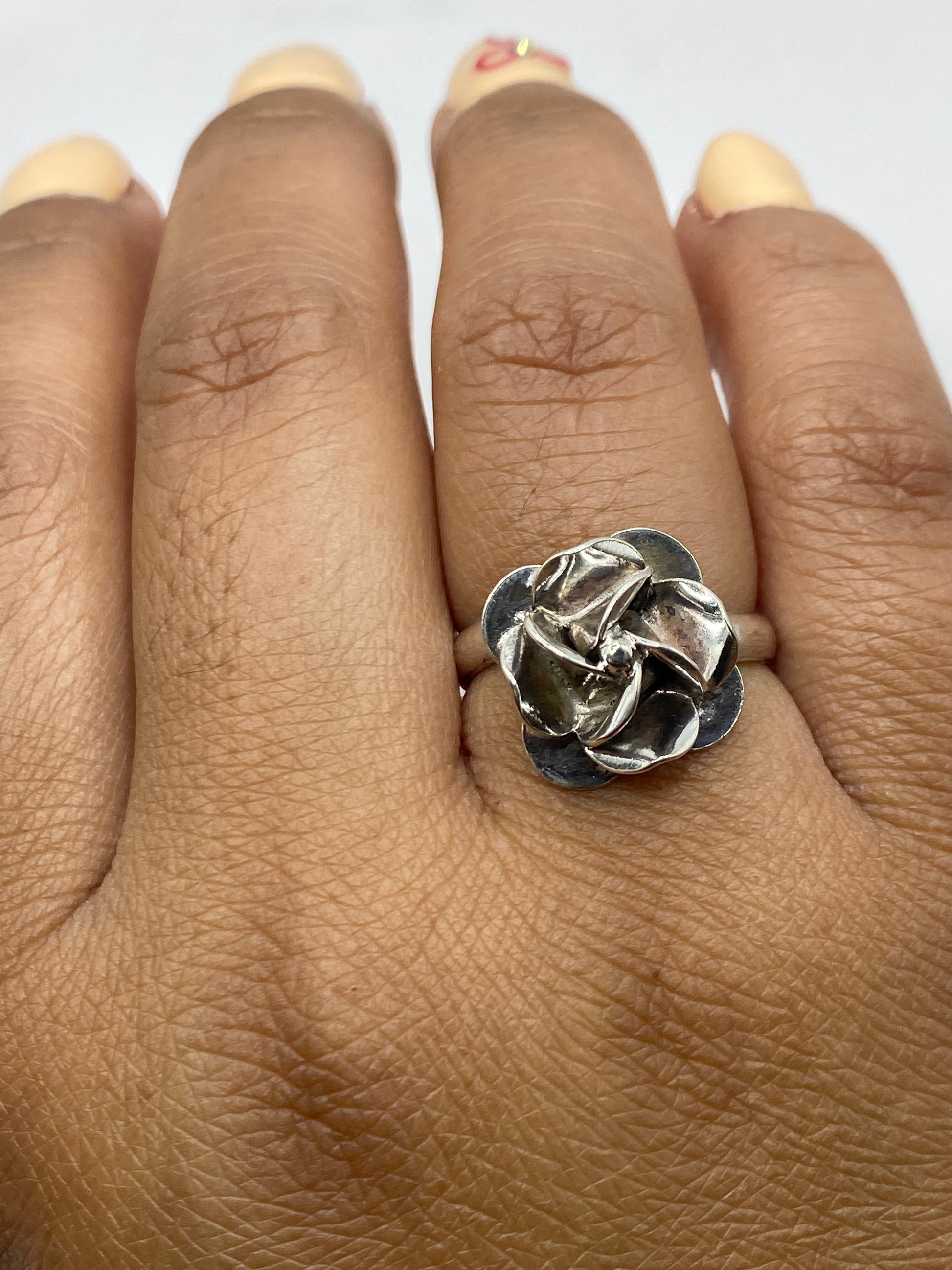 Anillo de plata rosa floral ajustable puesto en mano, mostrando el peso y volumen de la pieza