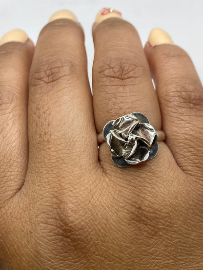 Anillo de plata rosa floral ajustable puesto en mano, mostrando el peso y volumen de la pieza