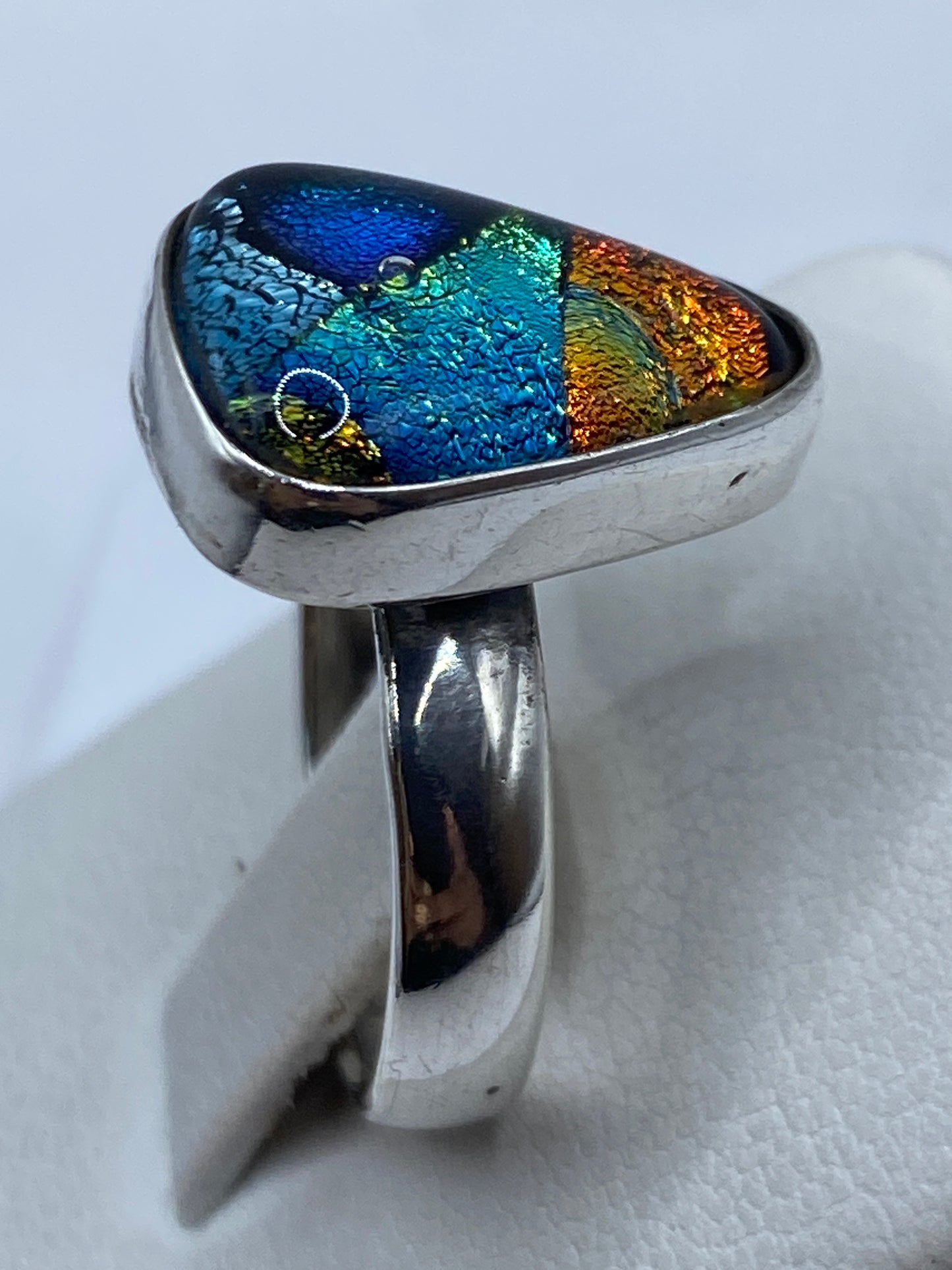 Anillo de plata .925 engastado en la mano, reflejando luz multicolor