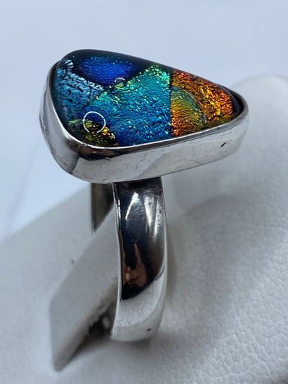 Anillo de plata .925 engastado en la mano, reflejando luz multicolor