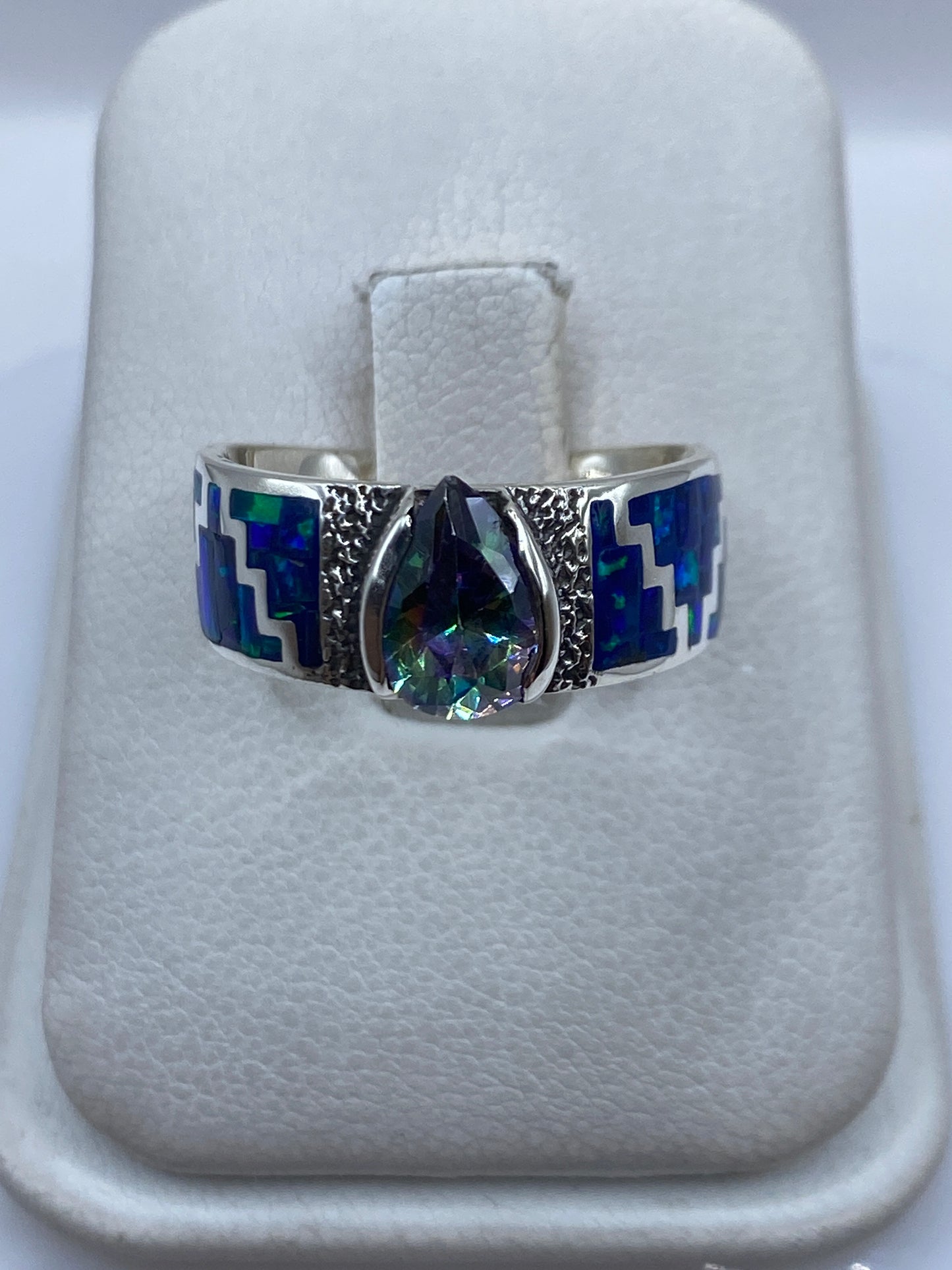 Anillo de plata .950 con ópalo de fuego azul en posición frontal sobre las manos