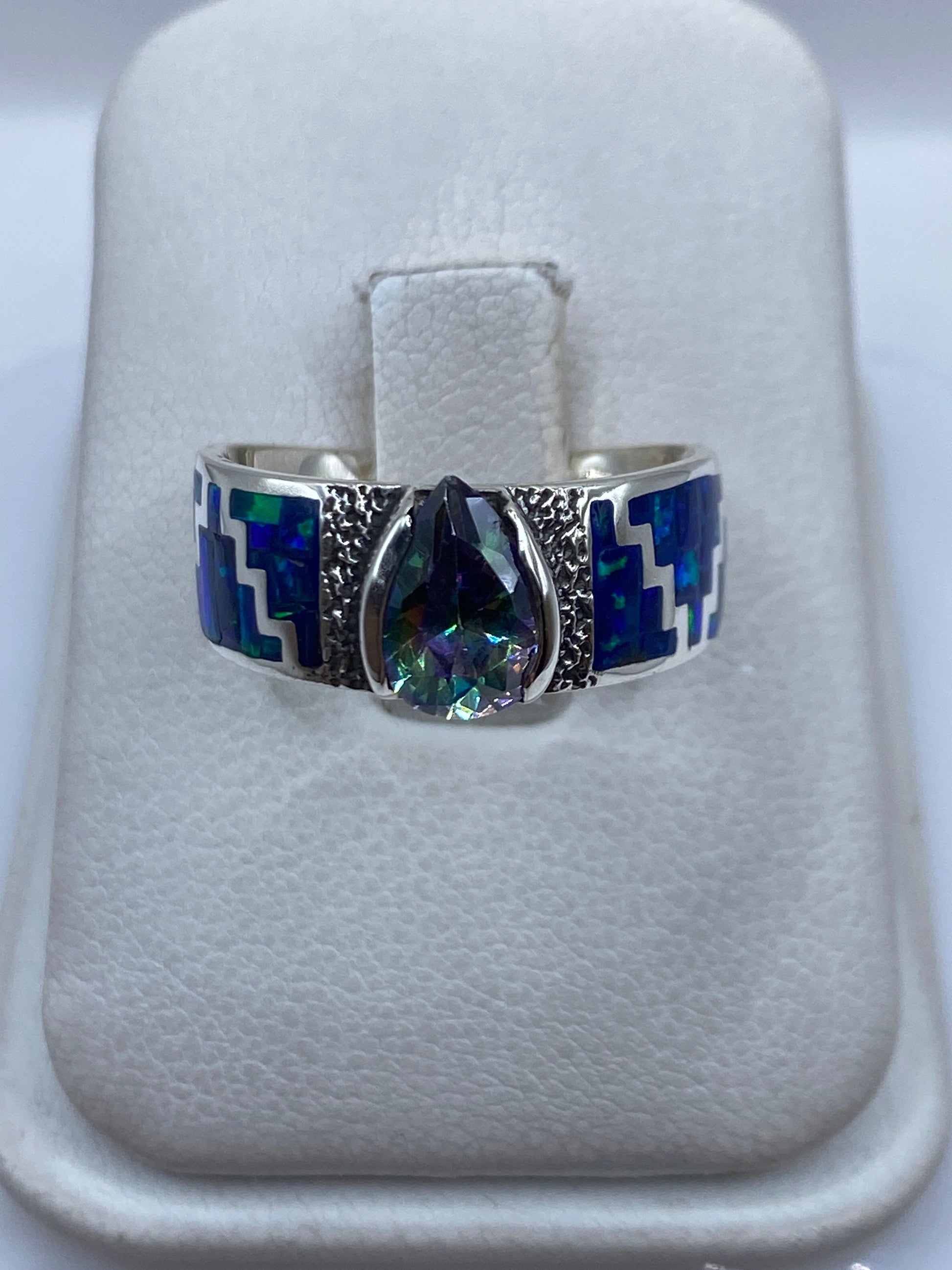 Anillo de plata .950 con ópalo de fuego azul en posición frontal sobre las manos