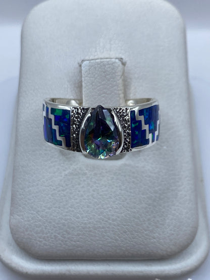 Anillo de plata .950 con ópalo de fuego azul en posición frontal sobre las manos