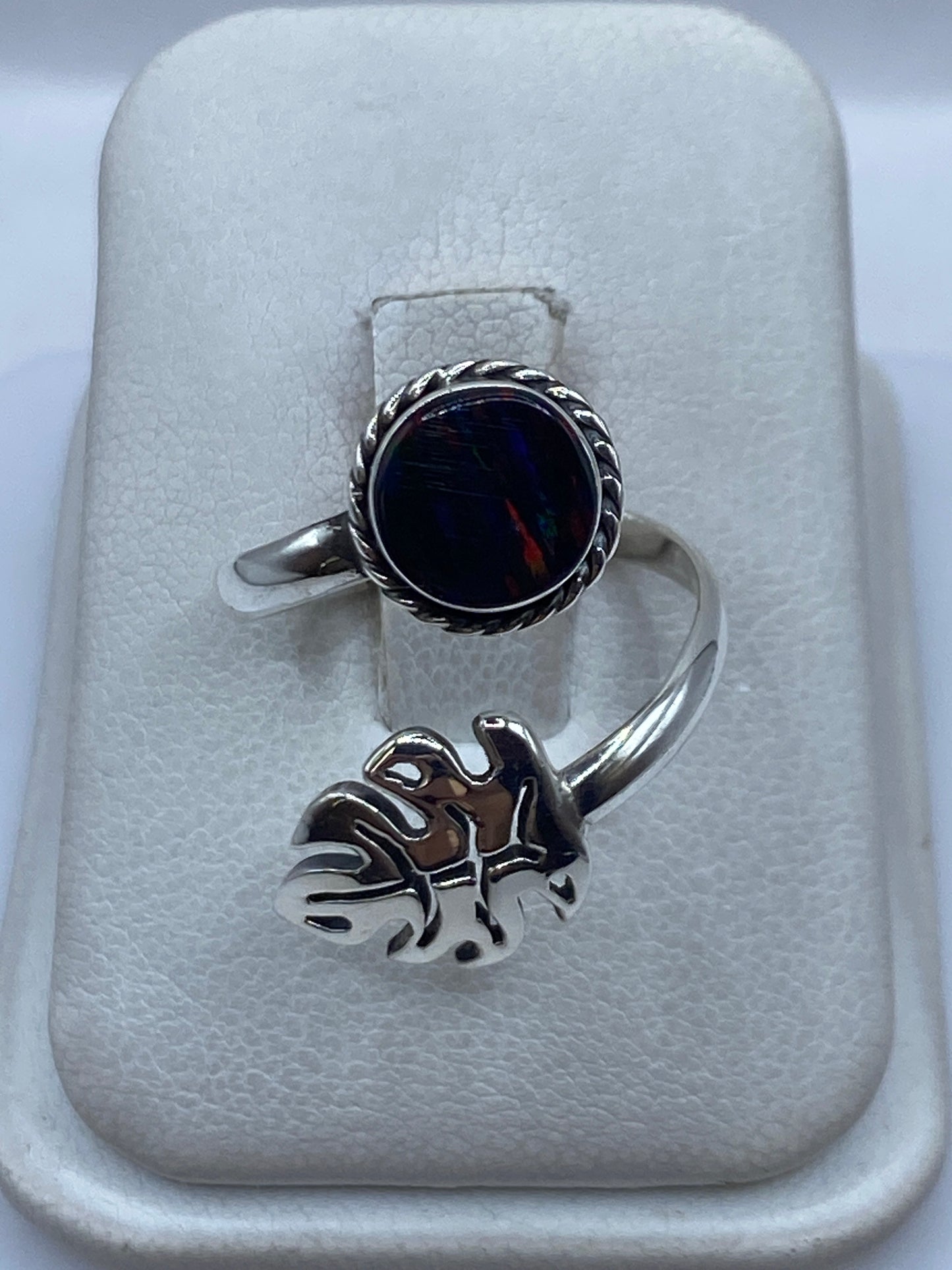 Anillo de plata ajustable con ópalo de fuego multicolor en la mano de una mujer