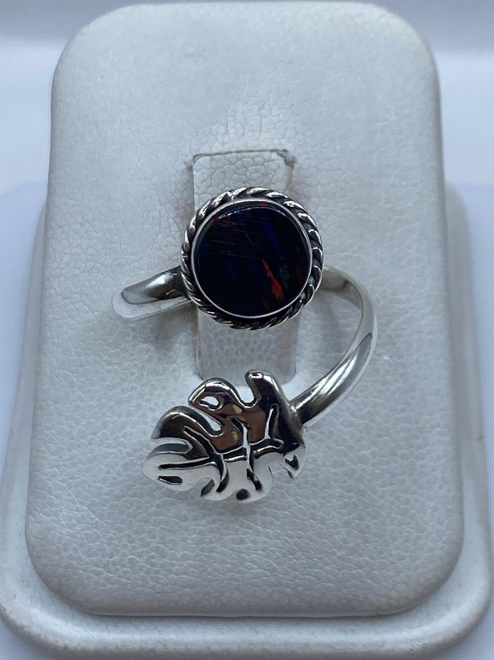 Anillo de plata ajustable con ópalo de fuego multicolor en la mano de una mujer