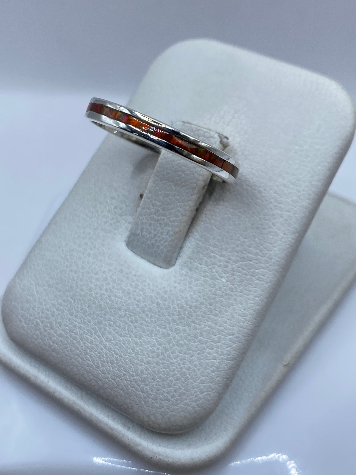 Anillo de plata con ópalo de fuego naranja en el dedo, mostrando el brillo naranja-rojo de la piedra