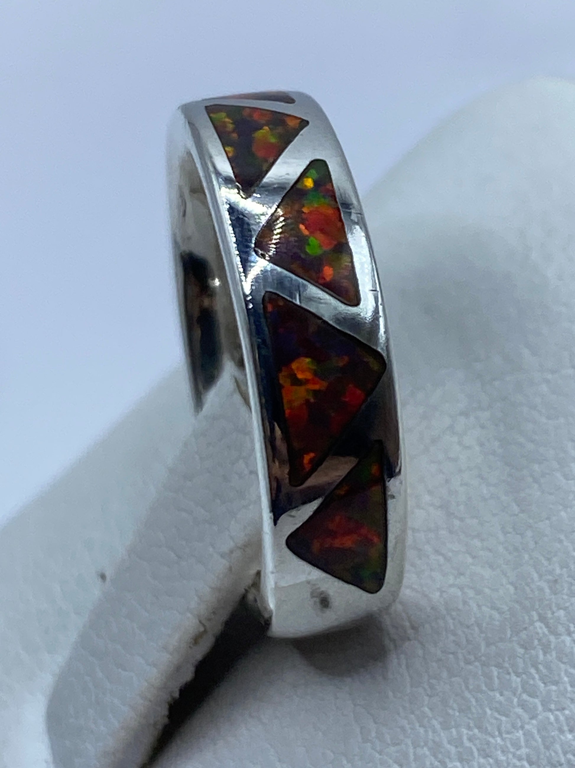 Anillo puesto en dedo mostrando los colores vivos del ópalo: naranja, rojo, verde y amarillo