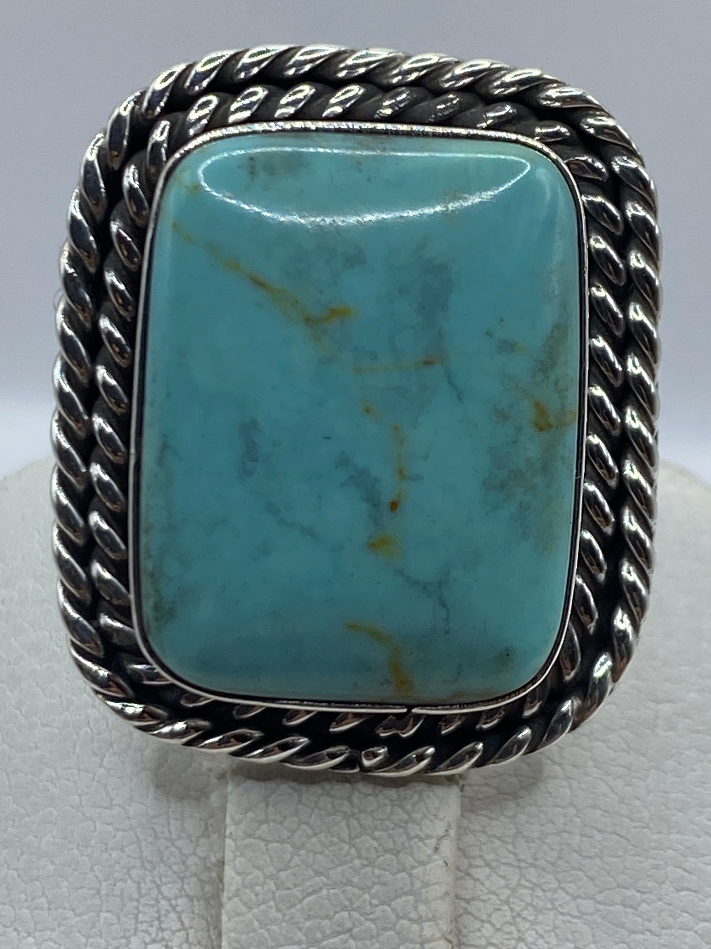 Anillo en dedo portando turquesa azul cielo y marco de plata retorcido de Taxco