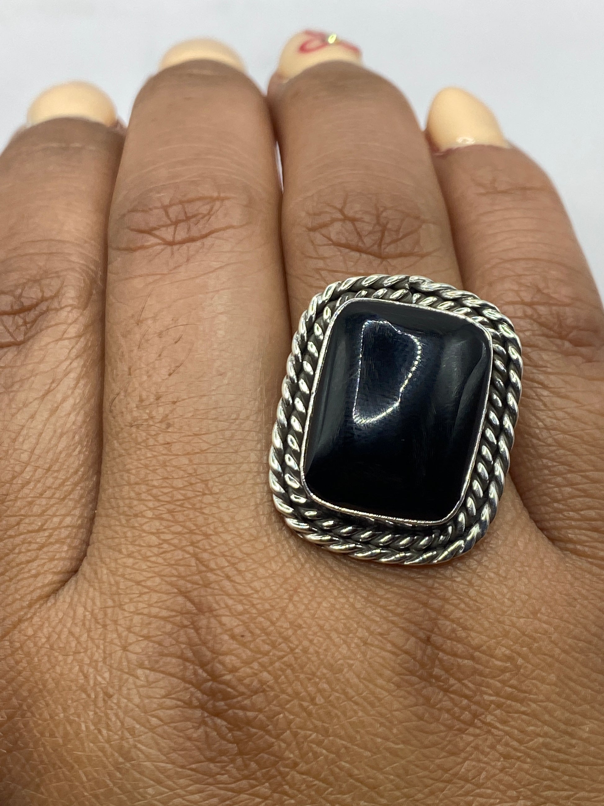Anillo en dedo mostrando el ónix negro brillante y el marco plateado