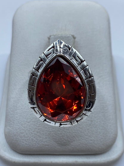 Anillo de plata con circonia roja facetada ajustable sobre fondo blanco