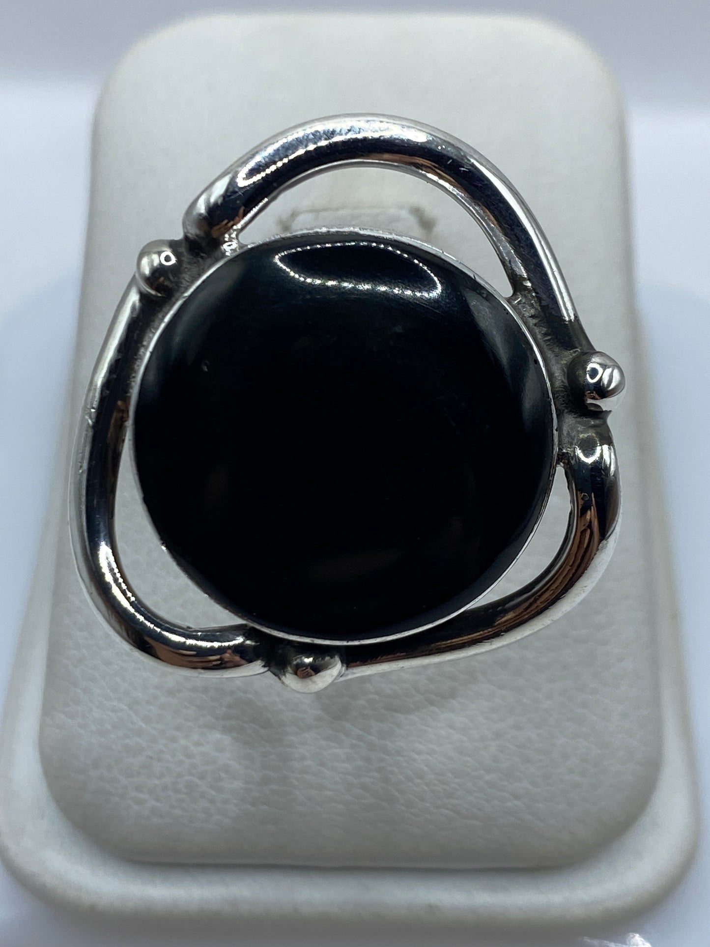 Anillo de plata ajustable con ónix negro pulido en la mano de una mujer