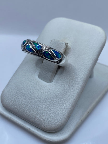 Anillo de ópalo azul en dedo, mostrando el juego de color natural de la piedra