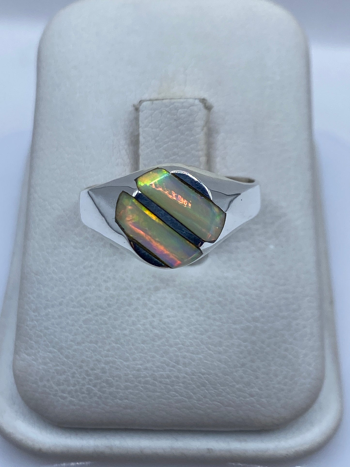 Anillo de plata .950 con ópalo de fuego iridiscente en la mano de una mujer