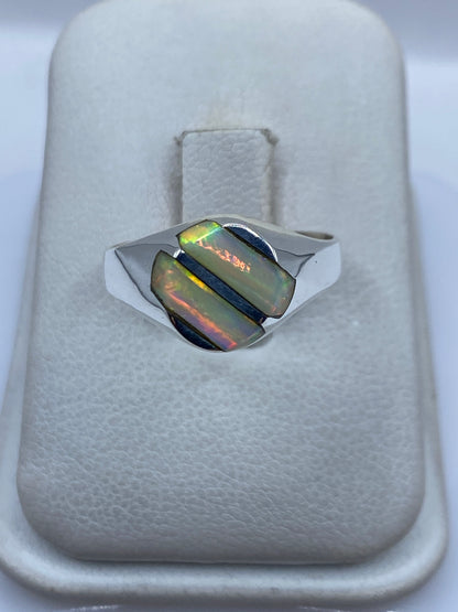 Anillo de plata .950 con ópalo de fuego iridiscente en la mano de una mujer