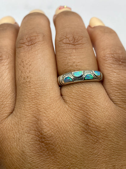 Anillo en dedo unisex mostrando el juego de luz azul verdoso del ópalo de fuego