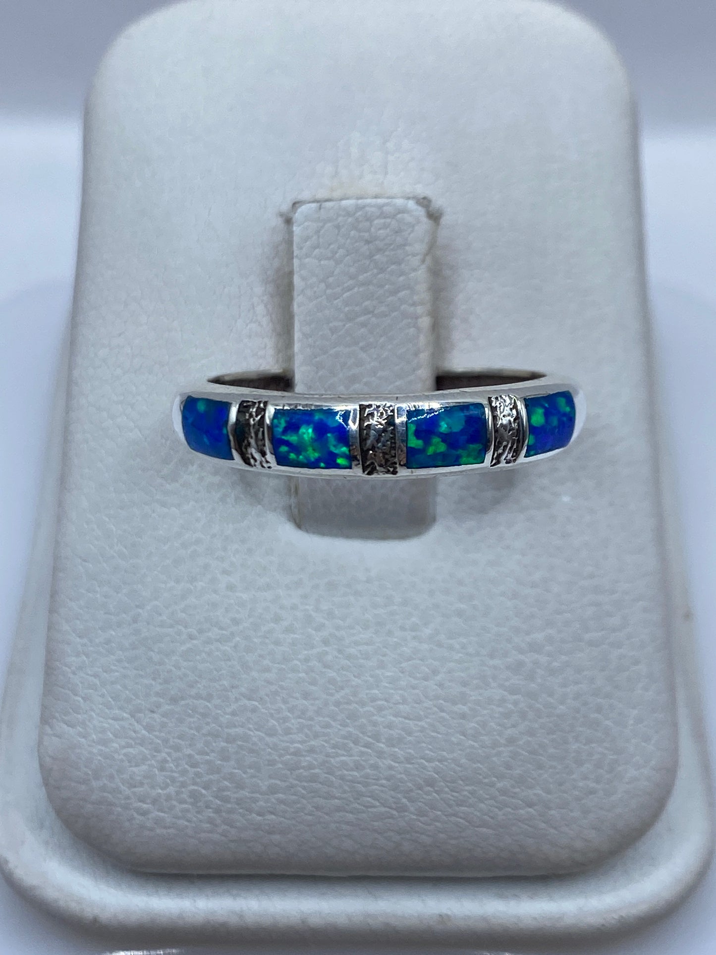 Anillo de plata .925 con ópalo de fuego azul en la mano de una persona, visto desde arriba