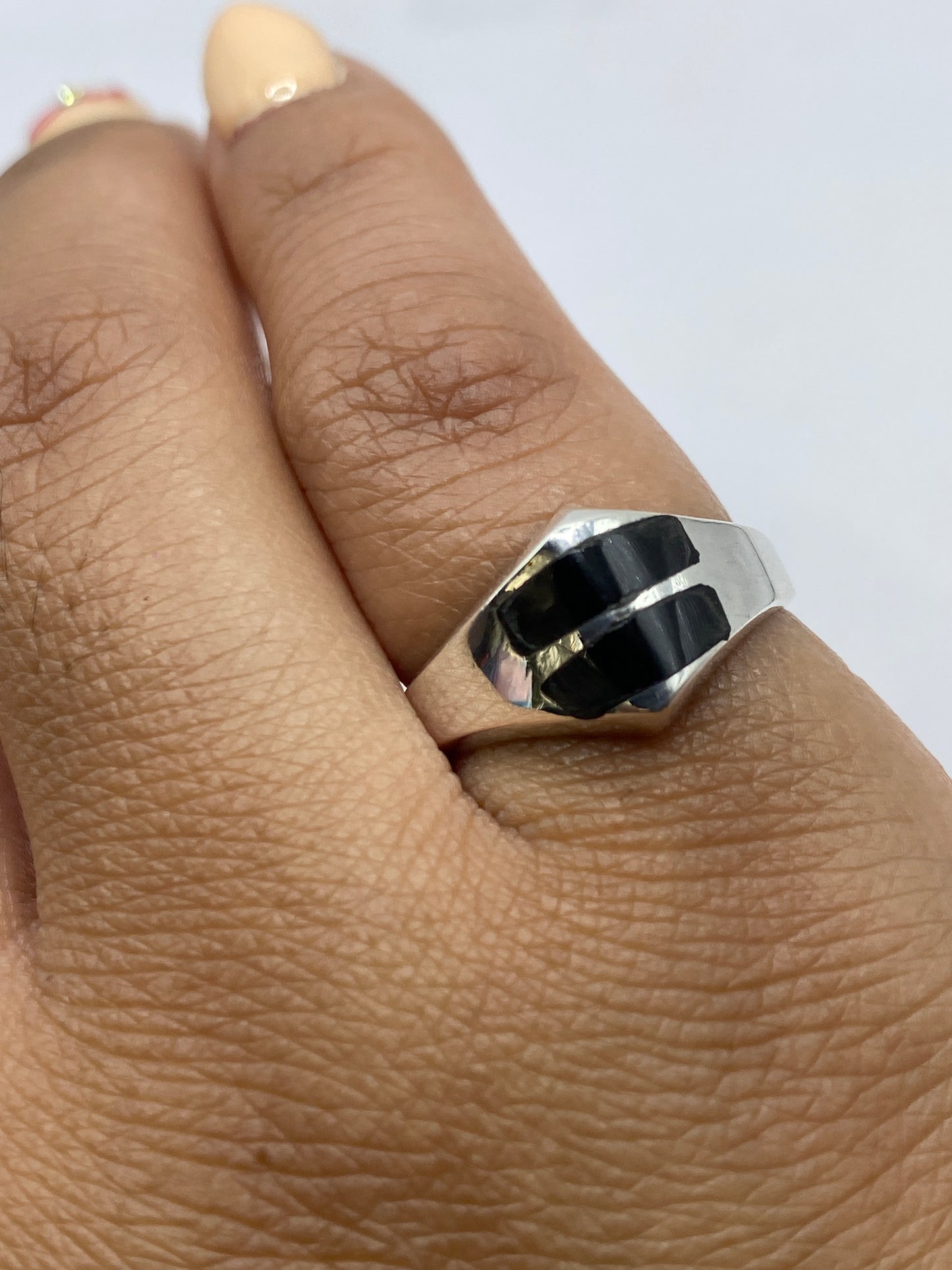 Anillo geométrico con ónix en mano, mostrando contraste de plata y piedra negra