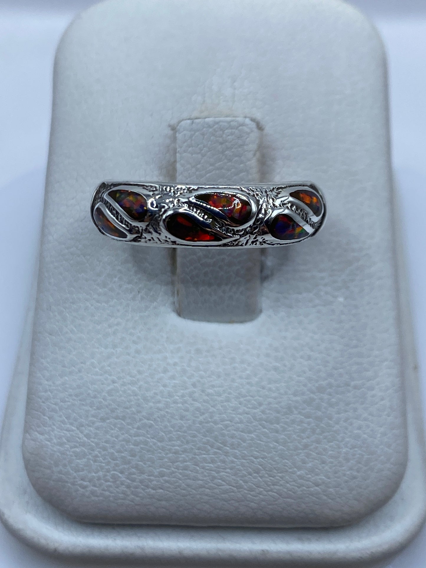 Anillo de plata .925 con ópalo de fuego multicolor engastado, visto de frente sobre dedo