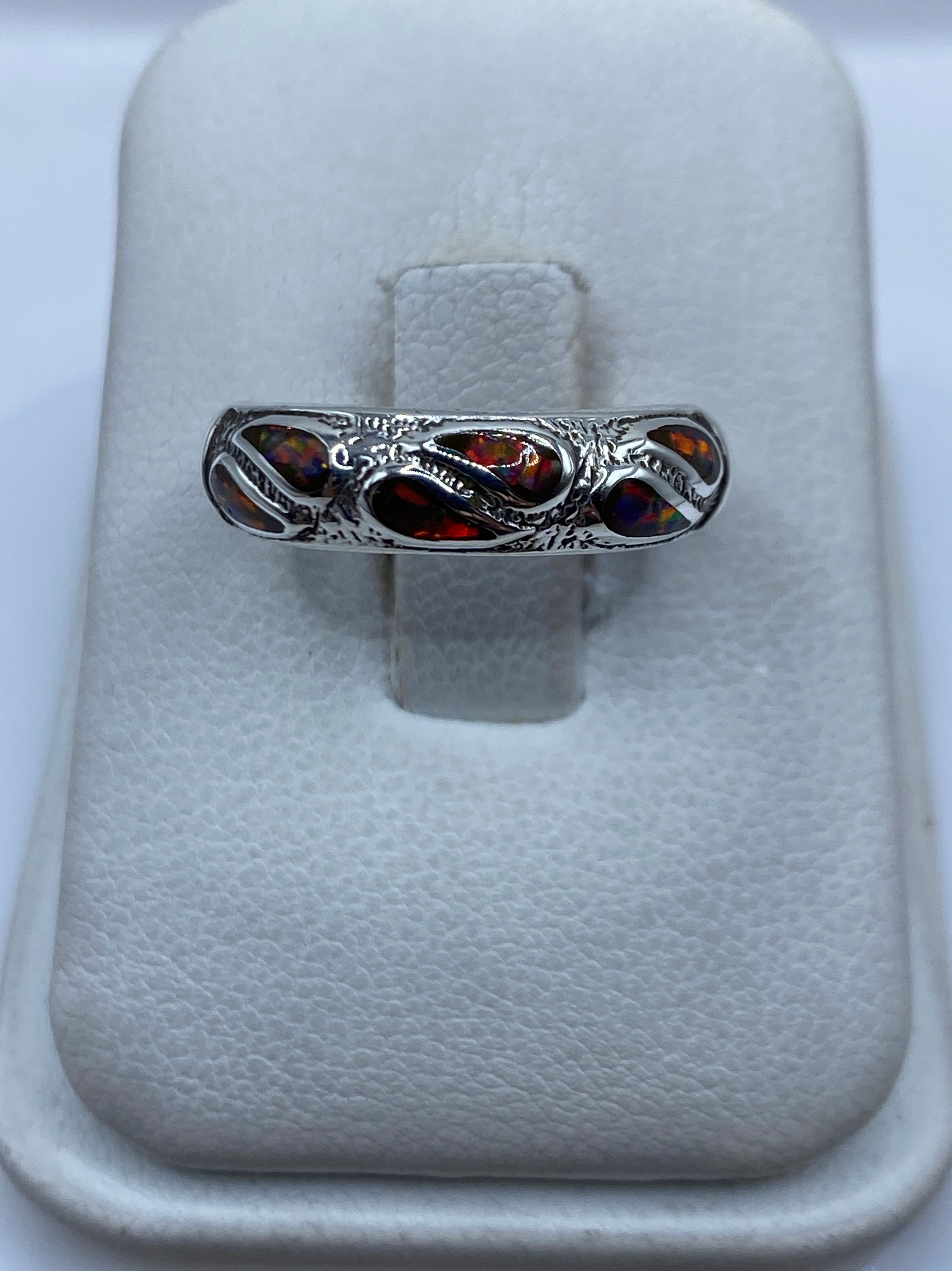Anillo de plata .925 con ópalo de fuego multicolor engastado, visto de frente sobre dedo