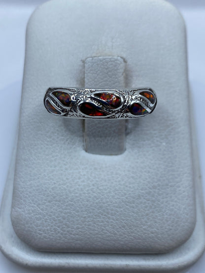 Anillo de plata .925 con ópalo de fuego multicolor engastado, visto de frente sobre dedo