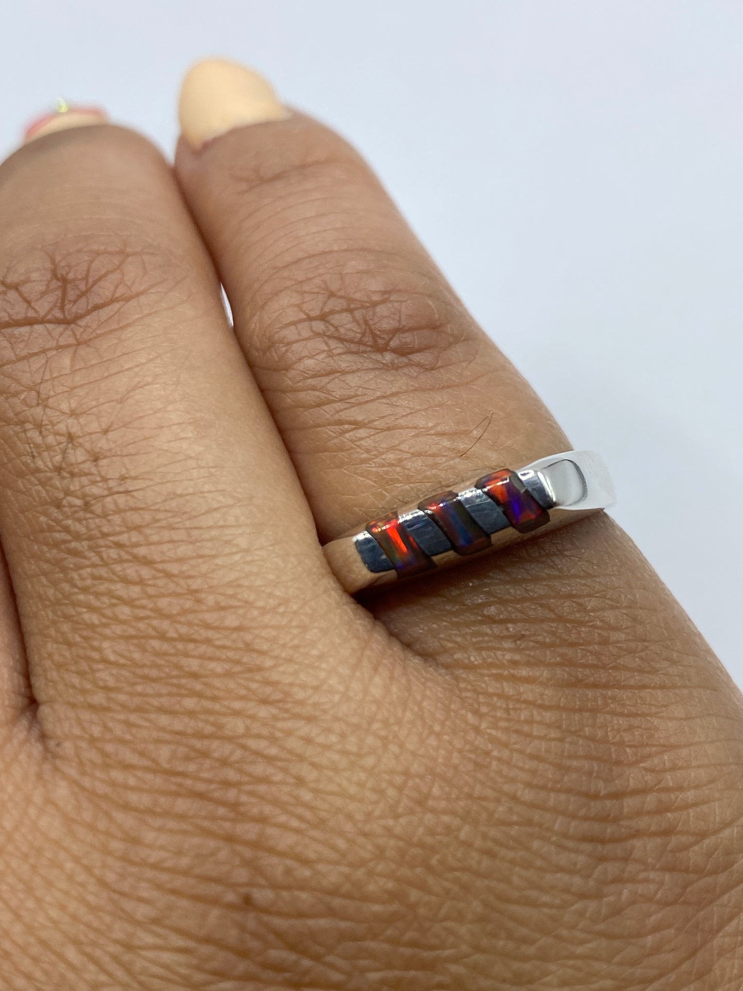 Anillo en la mano mostrando los tonos naranja y dorado del ópalo