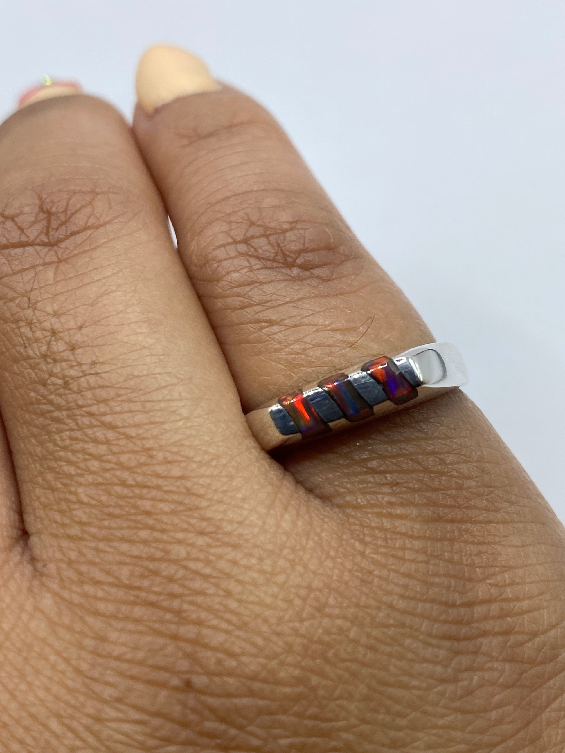 Anillo en la mano mostrando los tonos naranja y dorado del ópalo