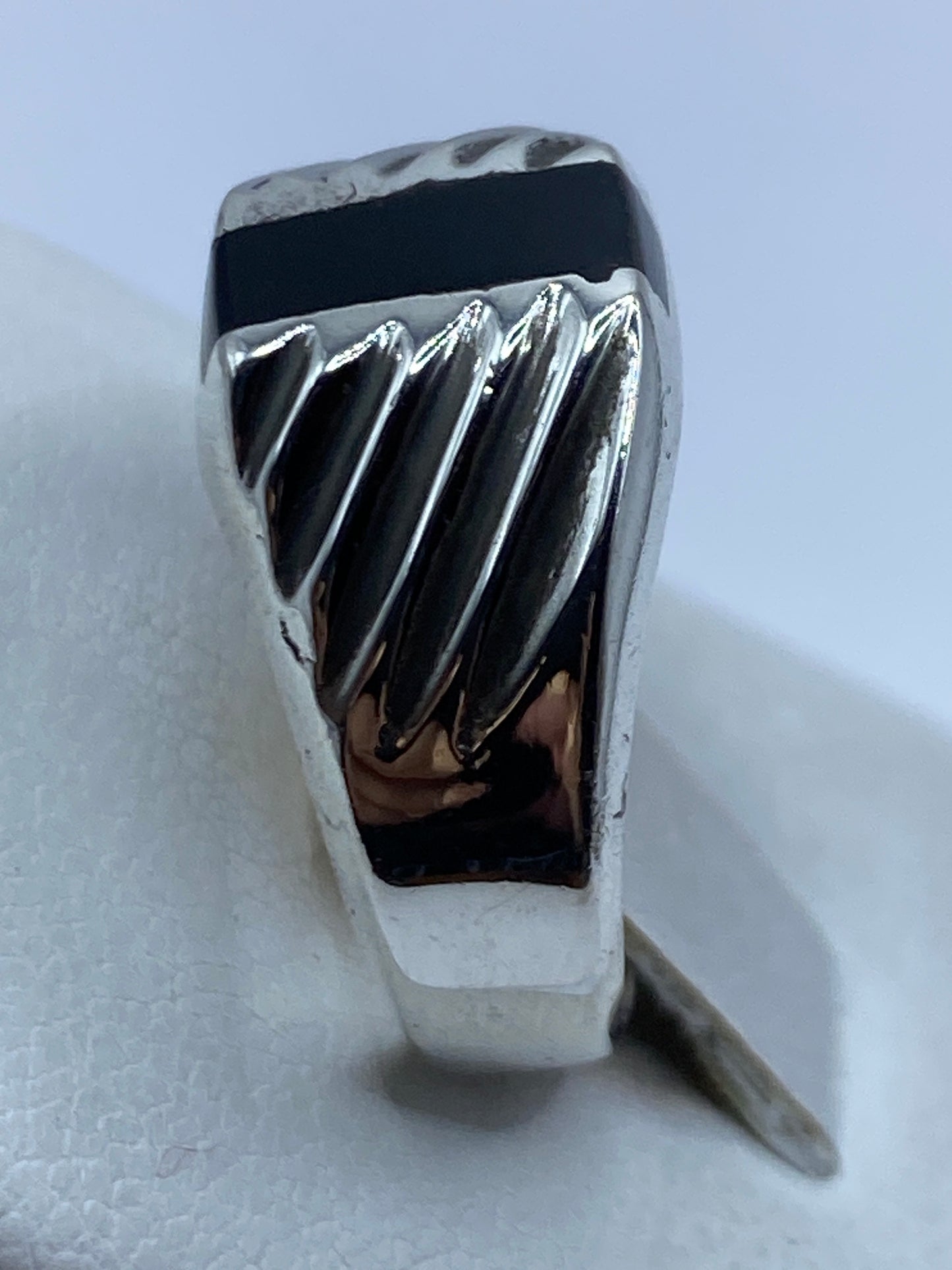 Anillo de ónix en plata en dedo, detalle del diseño con líneas de relieve